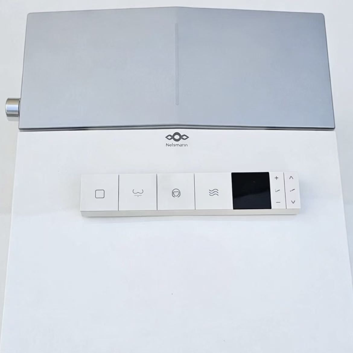 Télécommande murale du WC japonais Nelsmann KAKU posée sur l’abattant, avec écran et touches de lavage et de séchage
